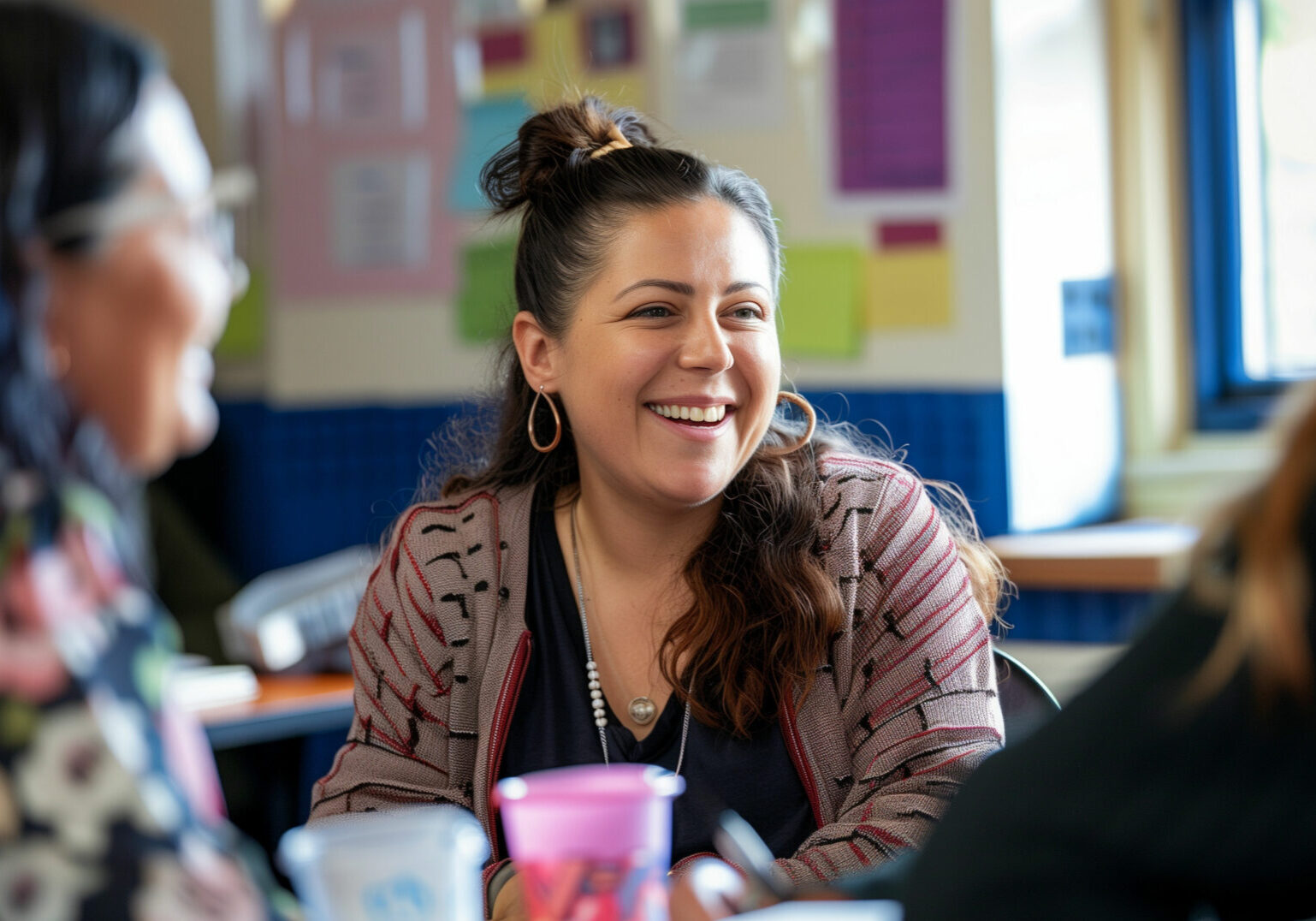 A Bravissimo teacher laughs while talking to a parent during a workshop at the school. They are both smiling and engaged in conversation.